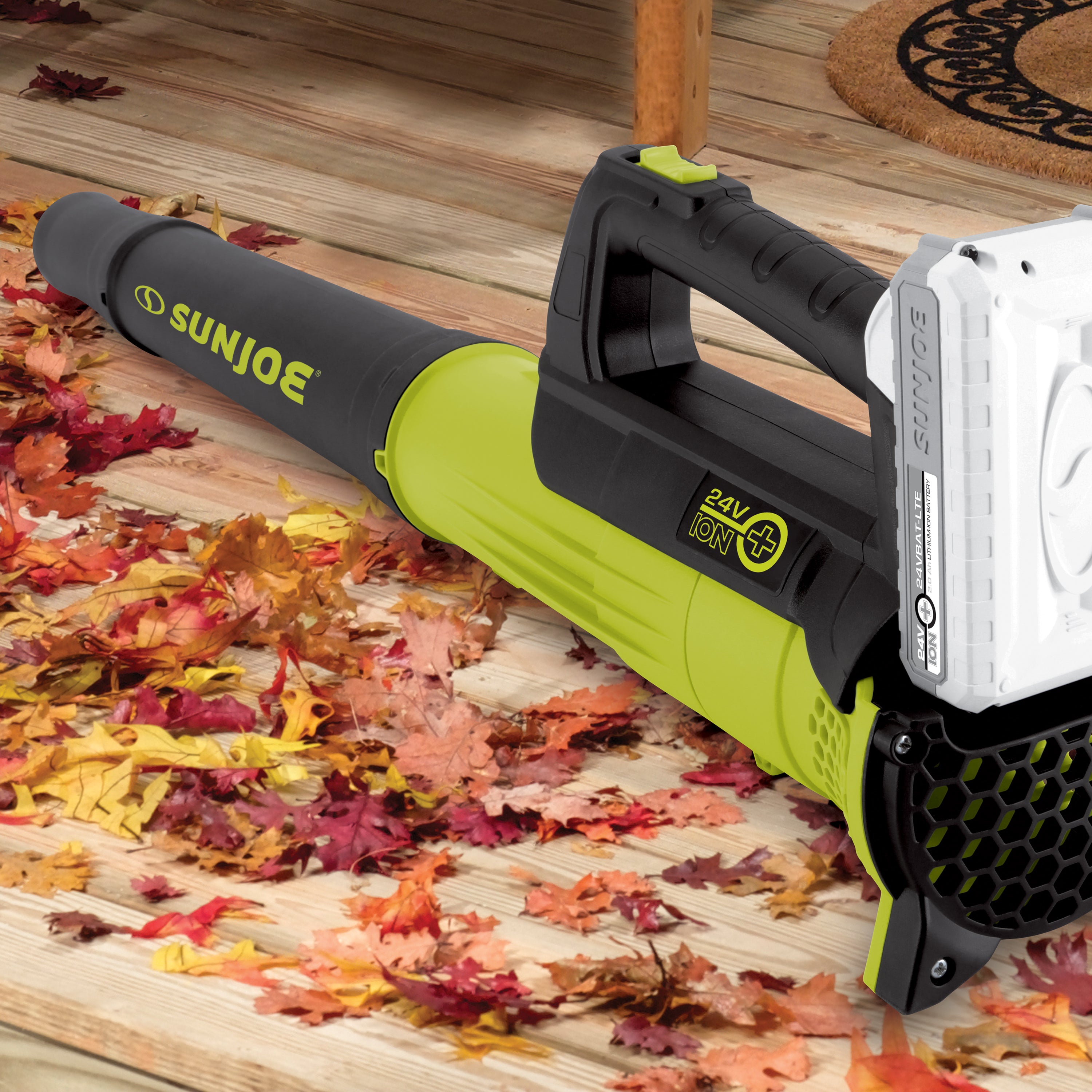 Sun Joe 24-volt cordless turbine leaf blower laying in leaves on a hardwood floor.