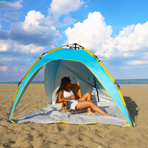 Woman relaxing in a chair on the beach while being shaded by the pop-up beach tent.