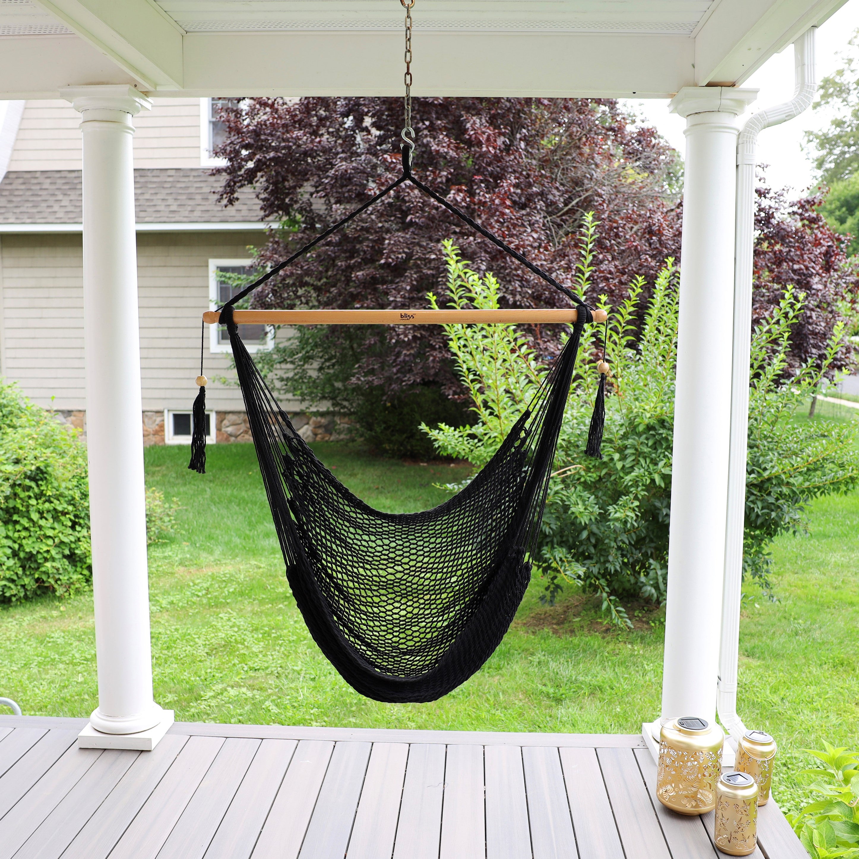 Bliss Hammocks 40-inch Black Island Rope Hammock Chair hanging on a front porch.