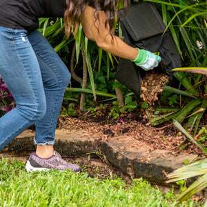 Person dumping mulch from the collection bag into her garden.