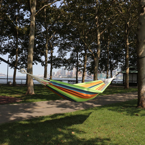 Bliss Hammocks 40-inch Wide Guacamole Stripe Hammock in a Bag hanging between two trees in a park.
