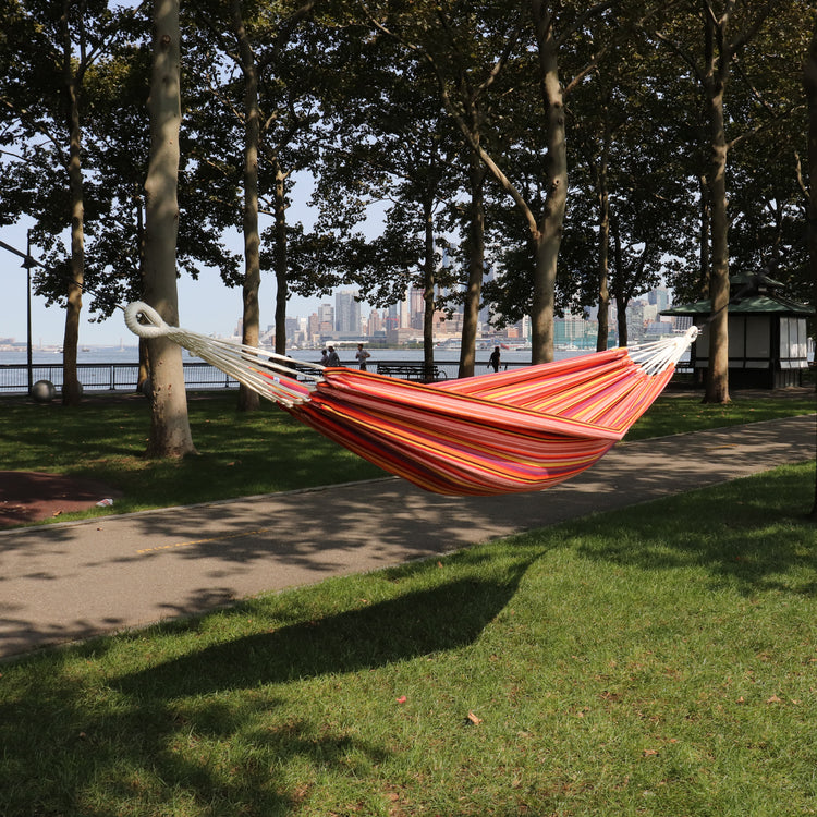 Bliss Hammocks 40-inch Wide Toasted Almond Stripe Hammock in a Bag hanging between two trees in a park.