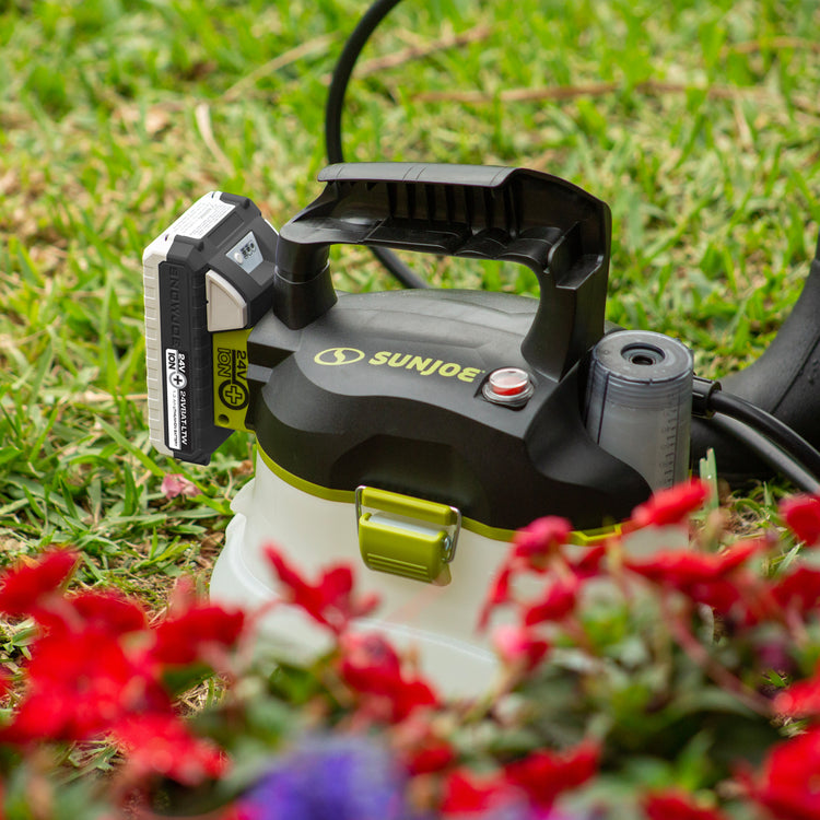 Sun Joe 24-volt cordless Multi-Purpose Chemical Sprayer Kit in the grass with flowers in the foreground.