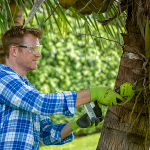 Man using the Sun Joe 24-volt Cordless Handheld and Long-Reach Pruner and Lopper without the pole to cut small twigs off a tree.