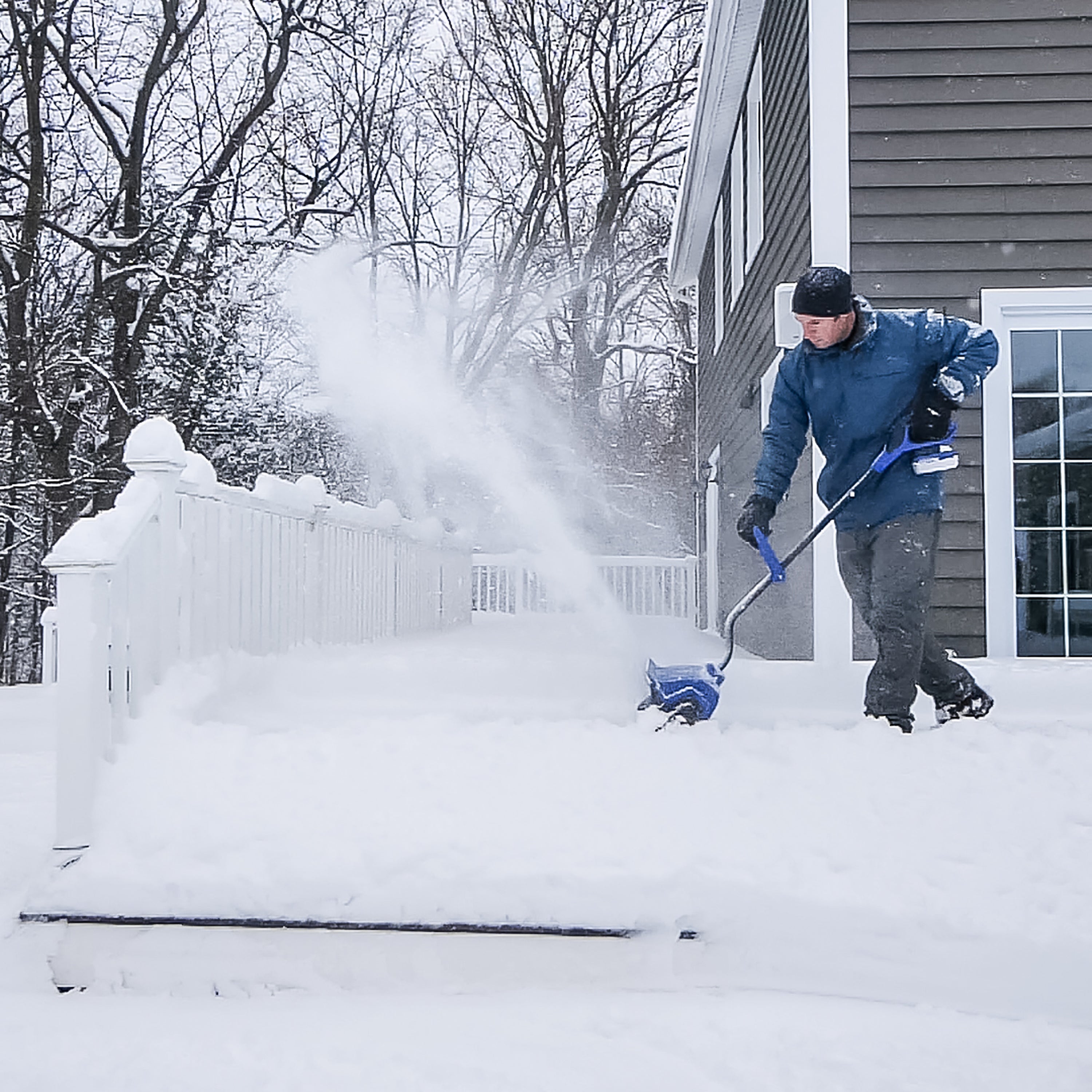 Person using the Snow Joe 24-volt cordless 13-inch snow shovel kit to clear snow off a patio.