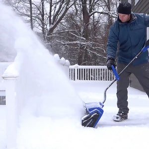 Man using the Snow Joe 24-volt cordless 13-inch snow shovel kit to clear snow off a deck.