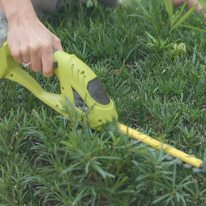 Person using the Sun Joe 24-volt Cordless handheld shrubber and trimmer to trim shrubbery,