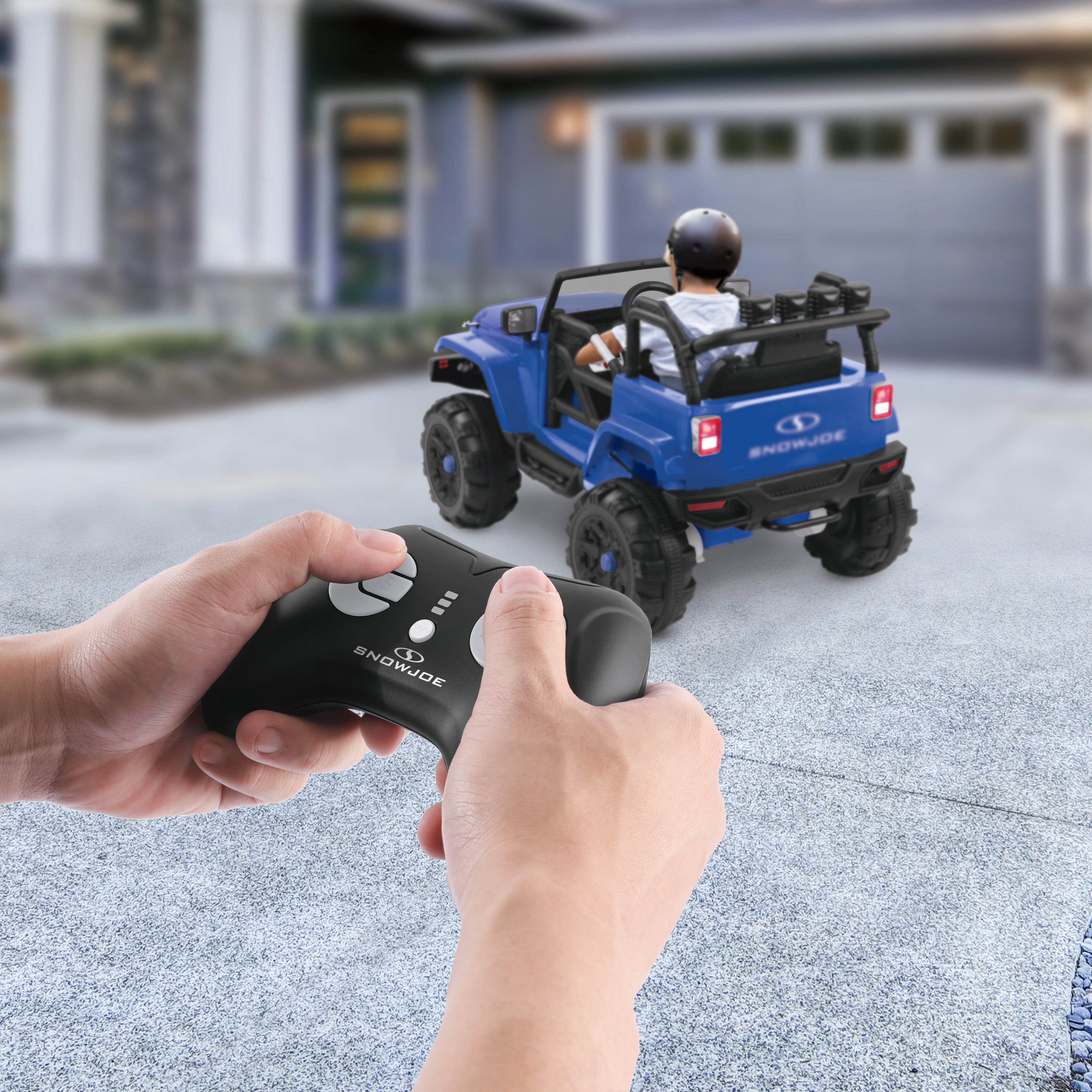 Person controlling the Snow Joe 24-Volt Ride On Kids Truck with the parental remote while a child is in it.