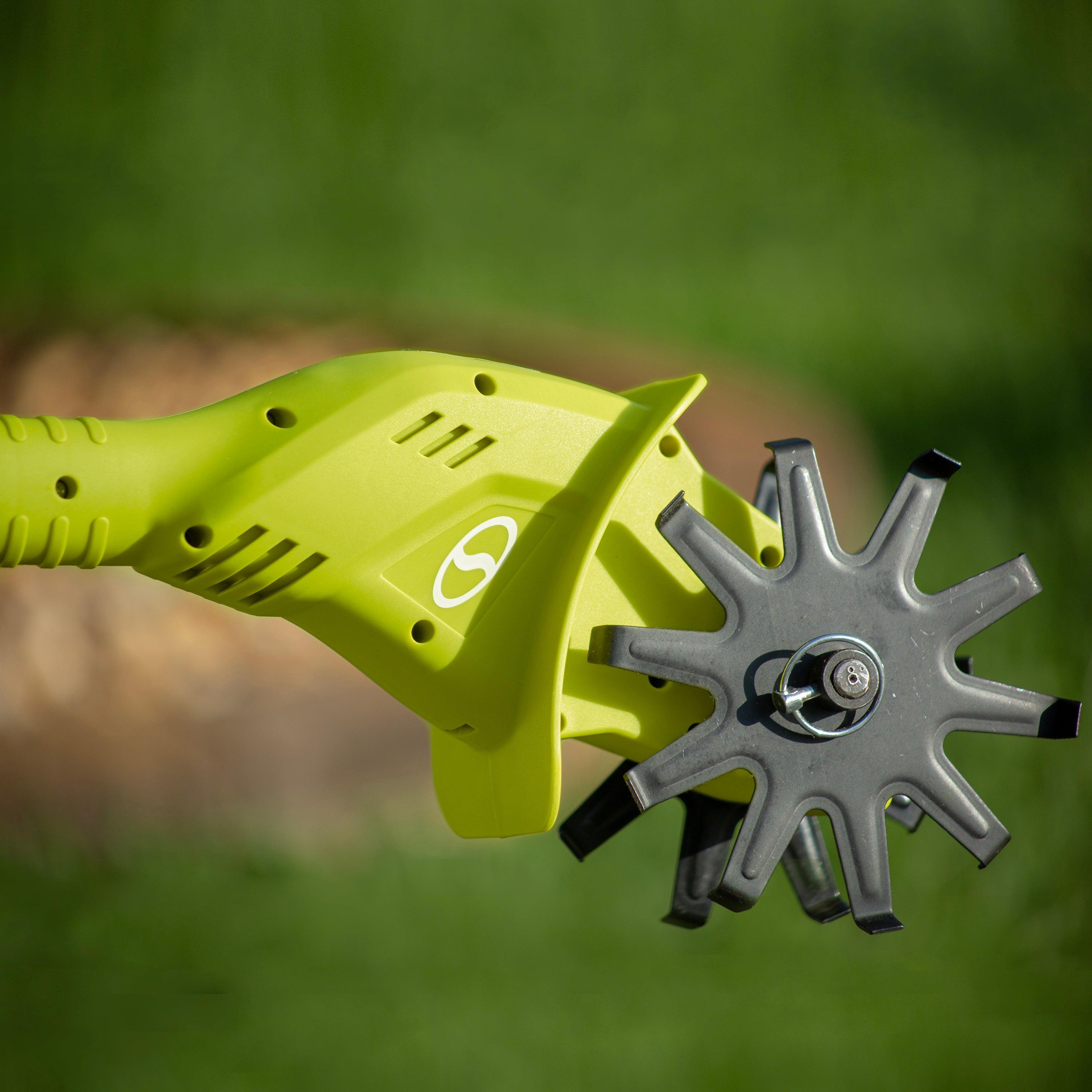 Close-up of the head and blades on the Sun Joe 24-volt cordless garden tiller and cultivating kit outside on a sunny day.