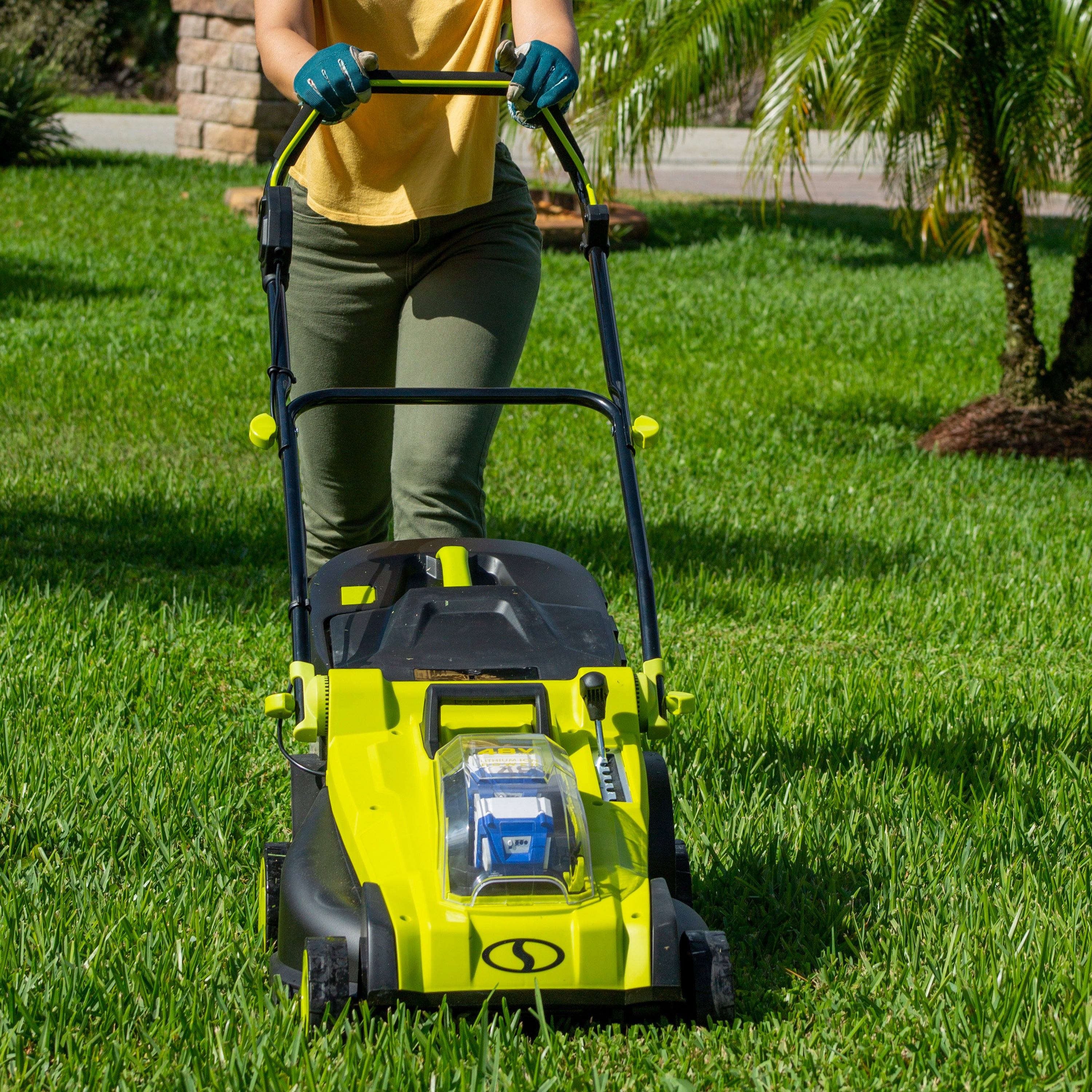 Person using the Sun Joe 48-volt cordless 17-inch lawn mower kit to mow their lawn.