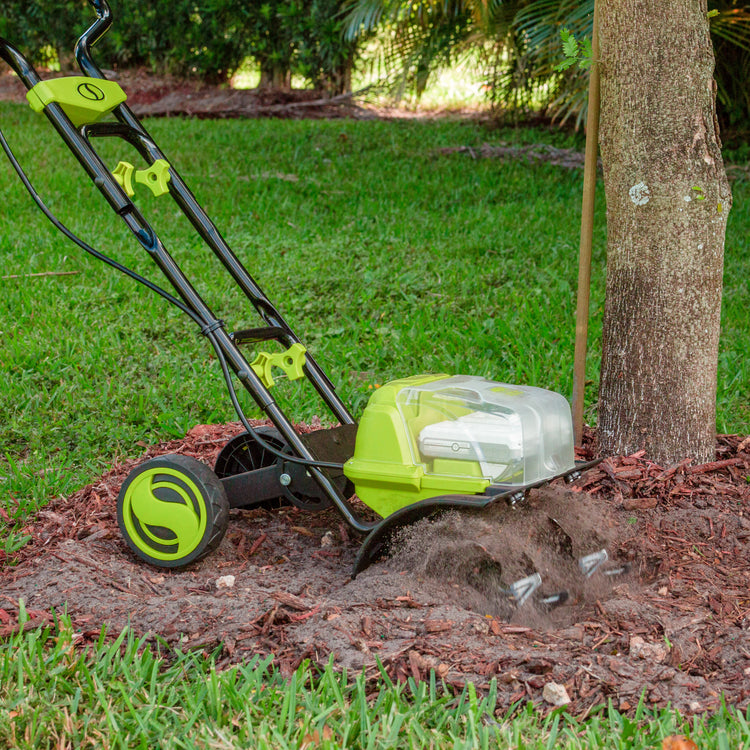 Sun Joe 48-volt Cordless 14-inch Garden Tiller/Cultivator Kit being used to till dirt around a tree.