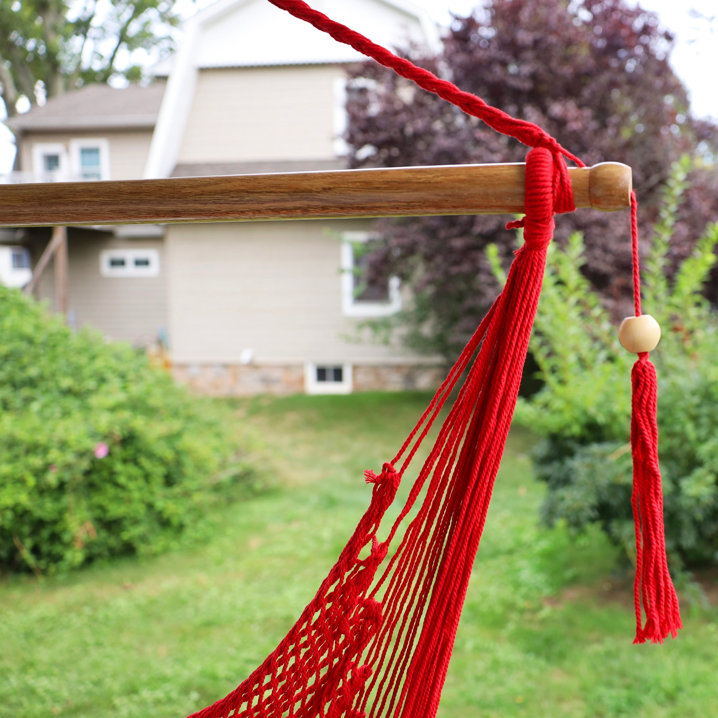 Close-up of the spreader bar and tassel on the Bliss Hammocks 40-inch Red Island Rope Hammock Chair.