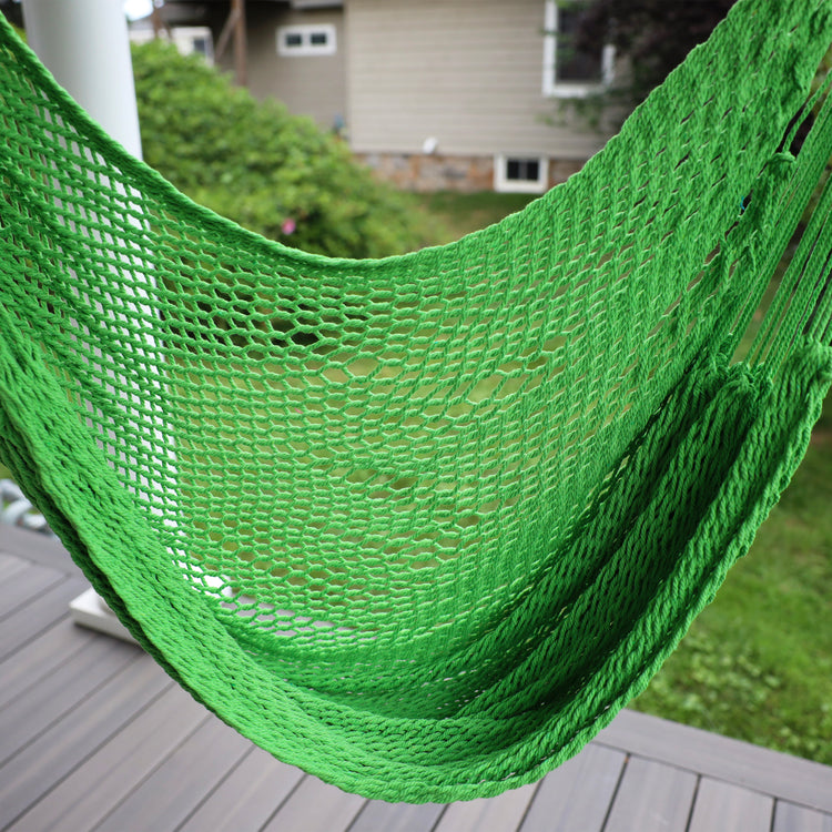 Close-up of the Bliss Hammocks 40-inch Light Green Island Rope Hammock Chair hung on a front porch.