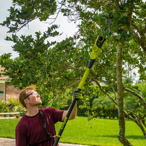 Man using the Sun Joe 24-volt cordless telescoping pole 10-inch chainsaw to cut branches from a tree.