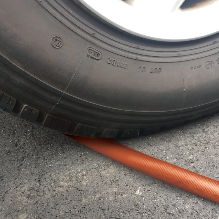 Car running over the Aqua Joe 75-foot non-expanding orange fiberjacket hose.