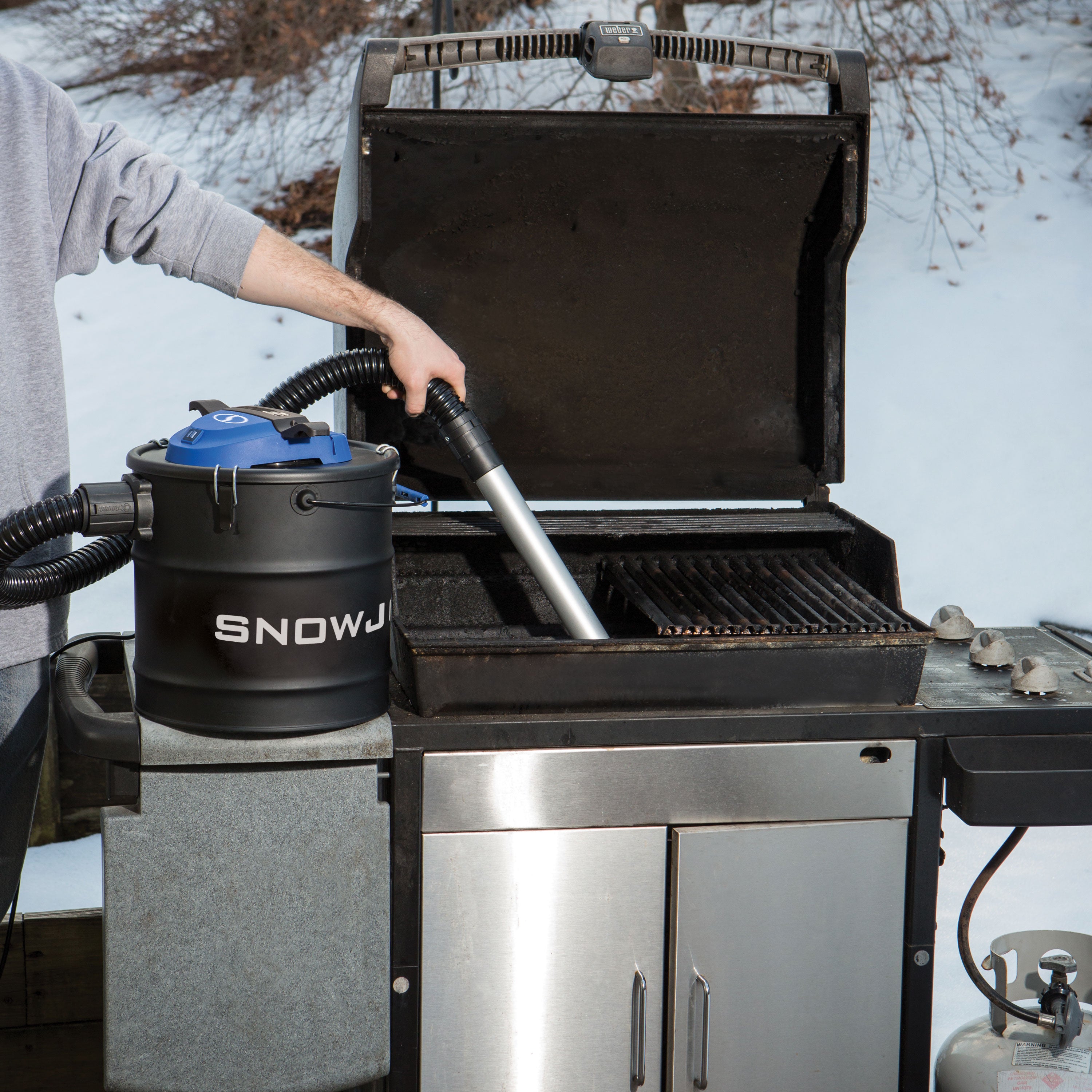 Snow Joe 4.8-gallon Ash Vacuum being used to clean the inside of a propane grill.