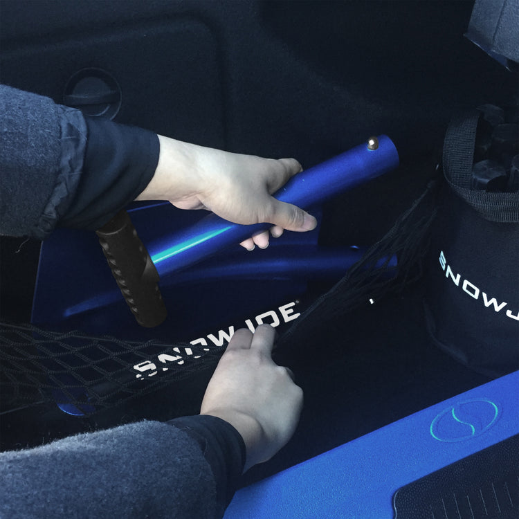 Person storing the utility shovel unassembled in the trunk of a car.