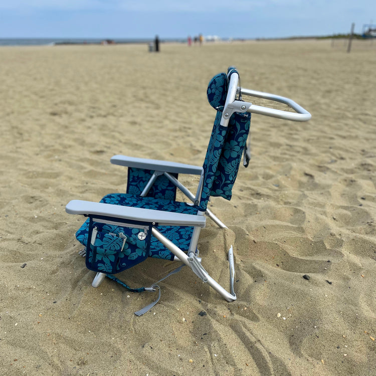 Side view of the blue flower backpack beach chair on the sand.
