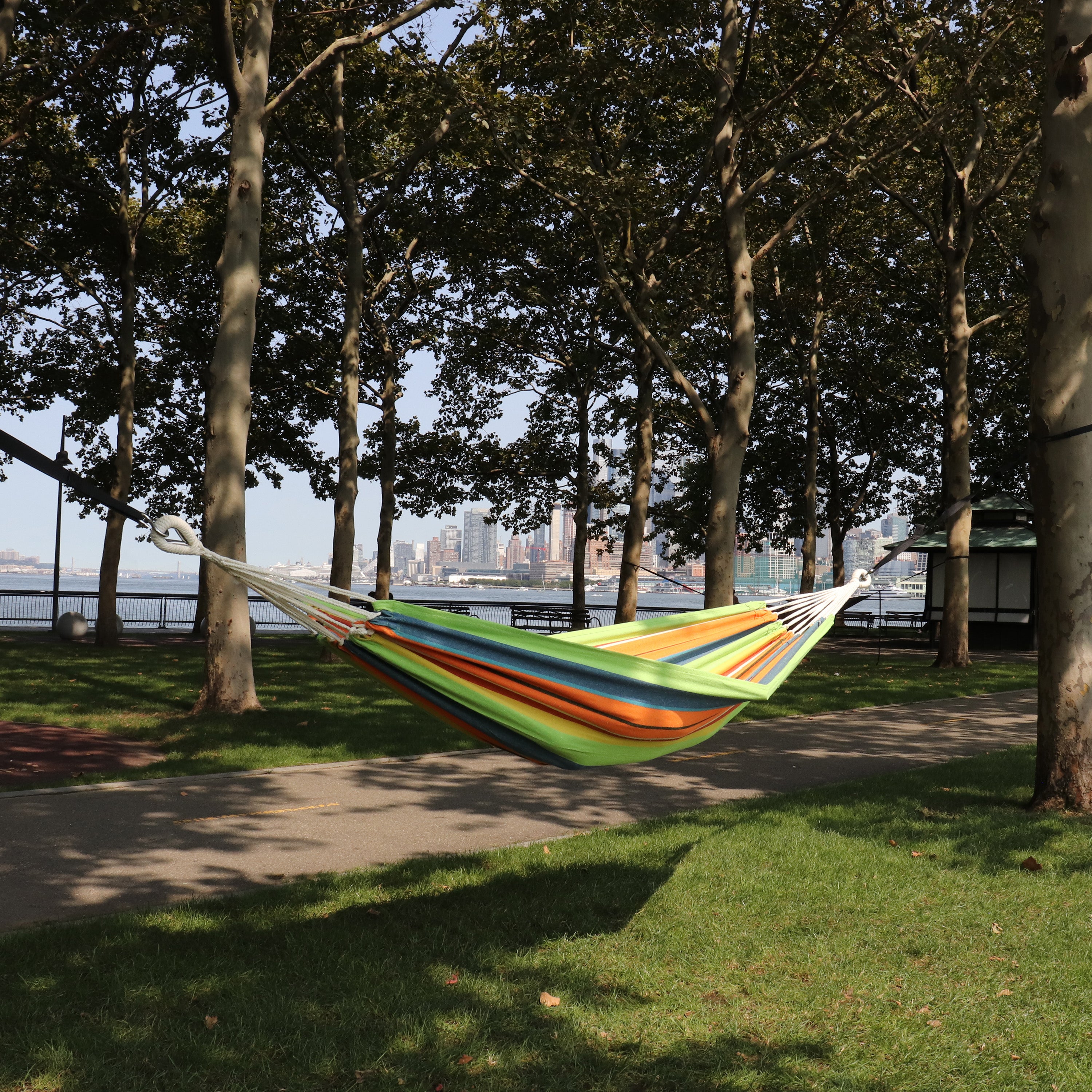 Bliss Hammocks 40-inch Wide Guacamole Stripe Hammock in a Bag hanging between two trees in a park.
