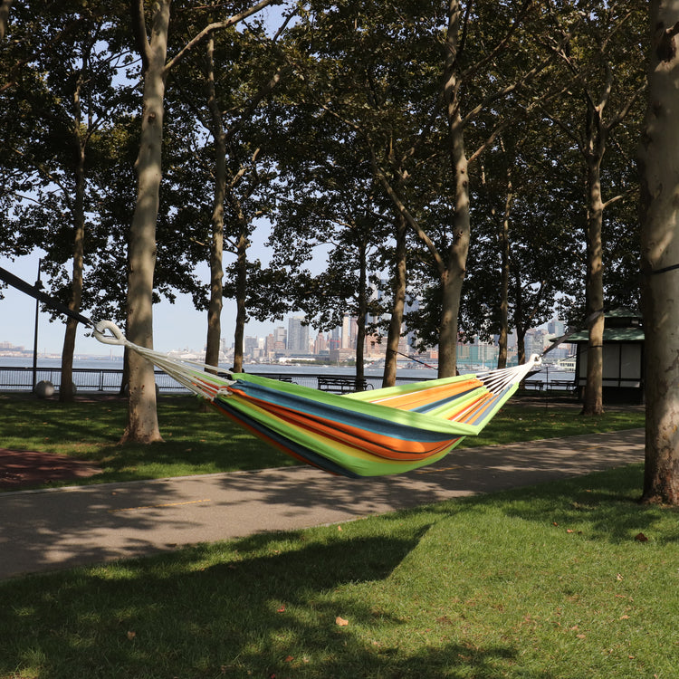 Bliss Hammocks 40-inch Wide Guacamole Stripe Hammock in a Bag hanging between two trees in a park.