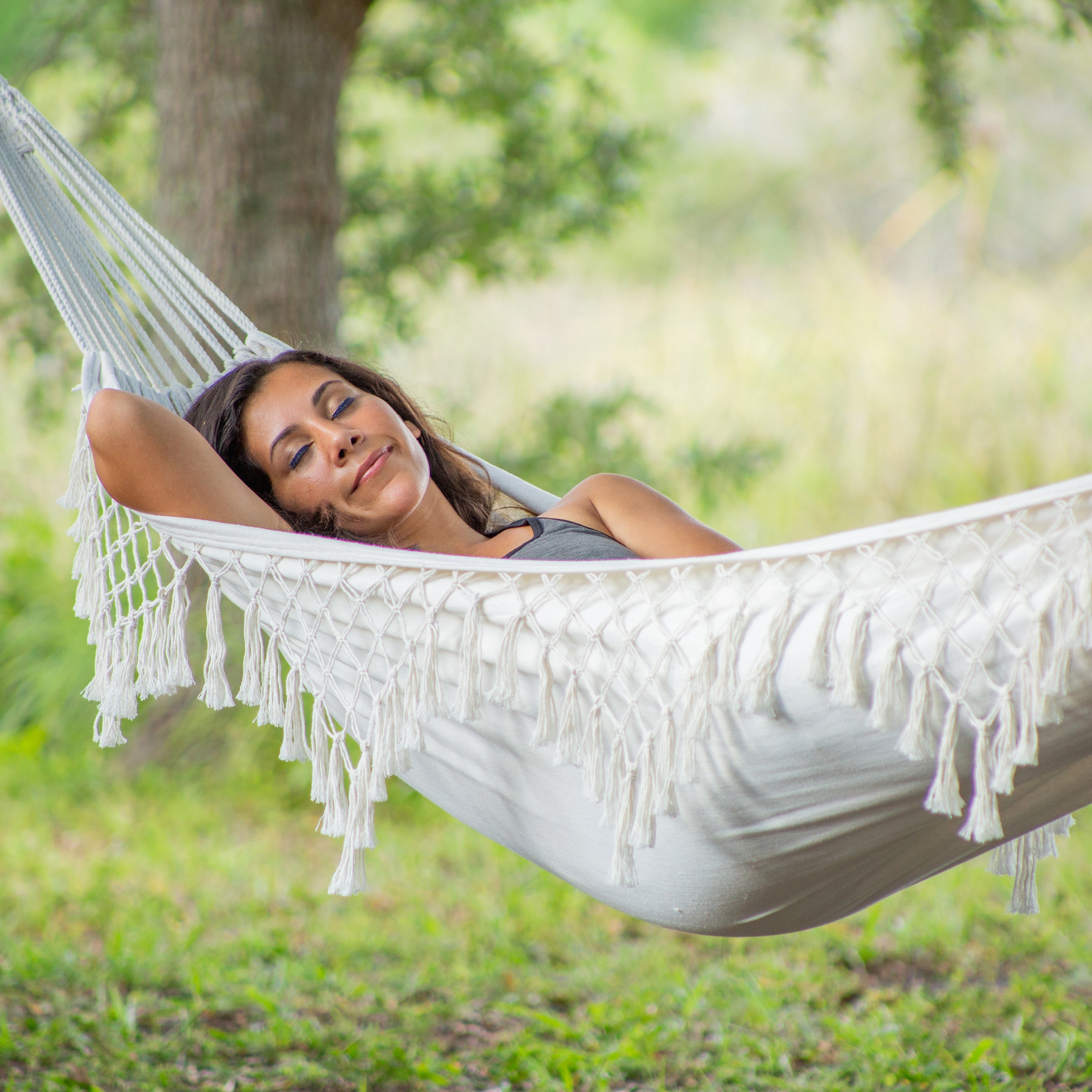 Woman relaxing outside in the Bliss Hammocks 40" Wide Hammock in a Bag with Fringe.