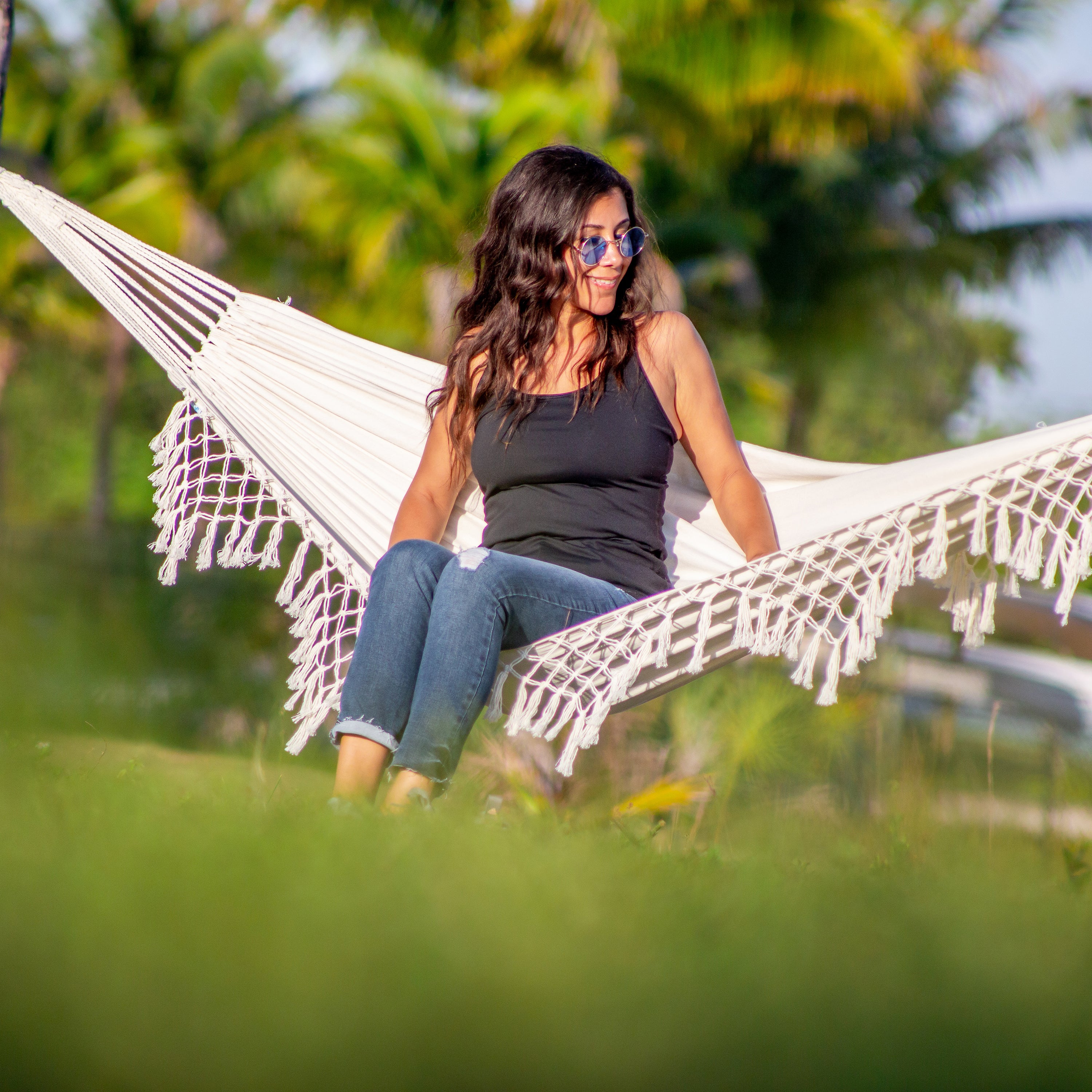 Woman sitting outside in the Bliss Hammocks 40" Wide Hammock in a Bag with Fringe.