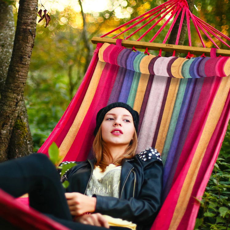 Woman relaxing outside in the Bliss Hammocks 48-inch Wide Tequila Sunrise Caribbean Hammock.