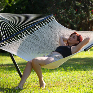 Woman sitting and laying back in the Bliss Hammocks 55-inch Wide 2-Person Weekender Deluxe Hammock.