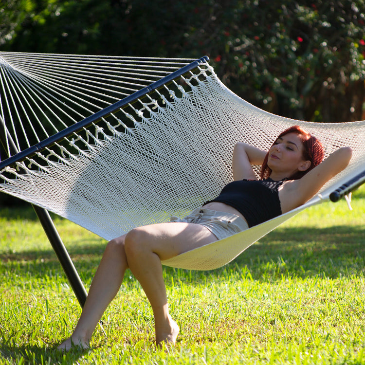 Woman sitting and laying back in the Bliss Hammocks 55-inch Wide 2-Person Weekender Deluxe Hammock.