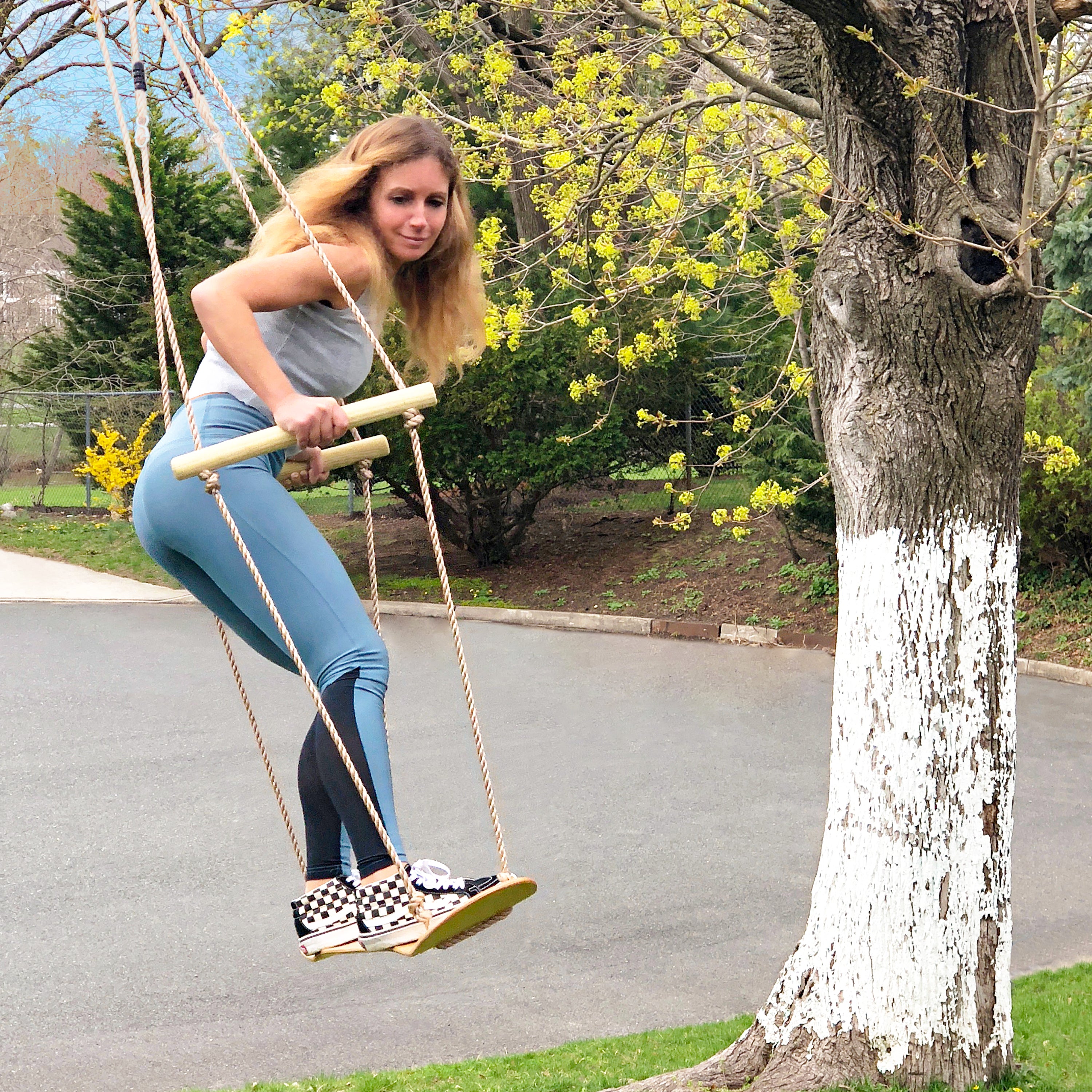 Woman swinging on the Bliss Outdoors Wooden Skateboard Swing.