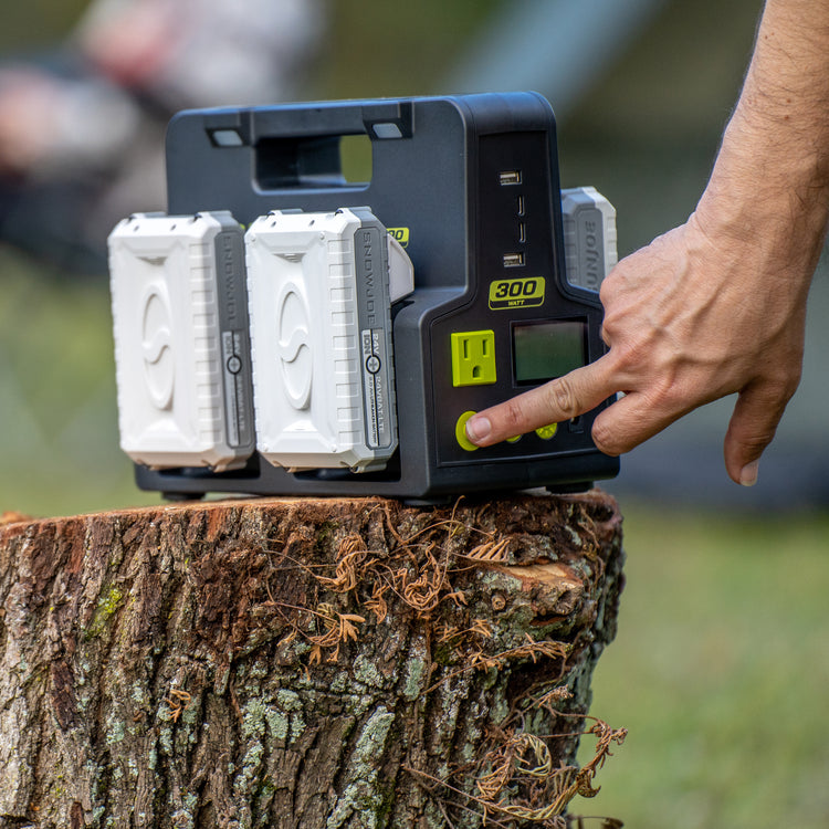 Person pressing the "on" button on the side of the Sun Joe 24-Volt Cordless Hot-Swap Powered Inverter Generator Power Station with batteries charging.