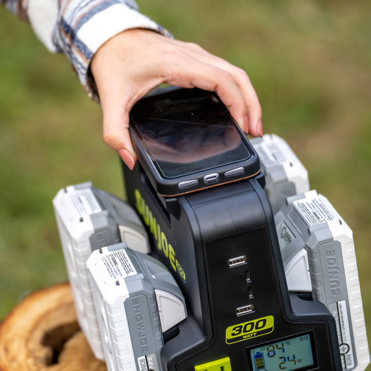 Person charging their cell phone on top of the Sun Joe 24-Volt Cordless Hot-Swap Powered Inverter Generator Power Station.