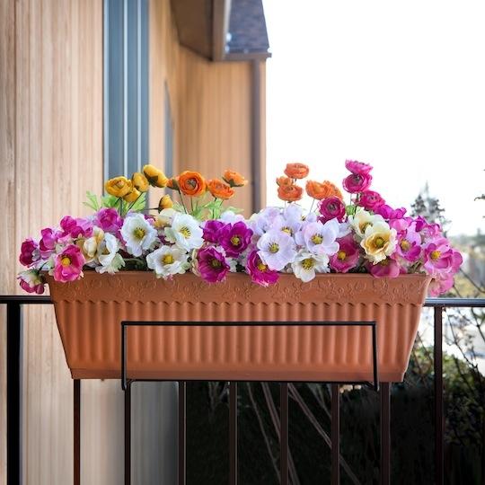 Sun Joe Deco Joe Flower Box Holder in Black holding flowers on a railing.