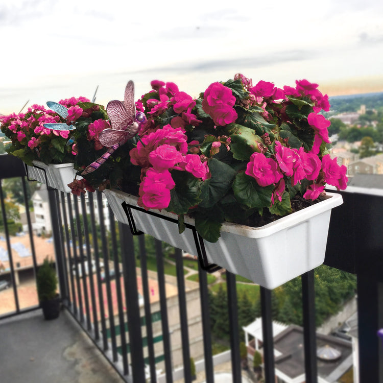 Sun Joe Deco Joe Adjustable Flower Box Holder in black holding flowers on a balcony railing.