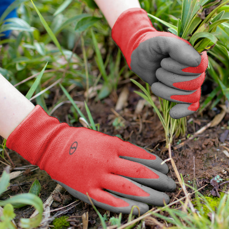 Sun Joe 3-pack of Nitrile-Palm Reusable Red Gloves being used for planting in a garden.