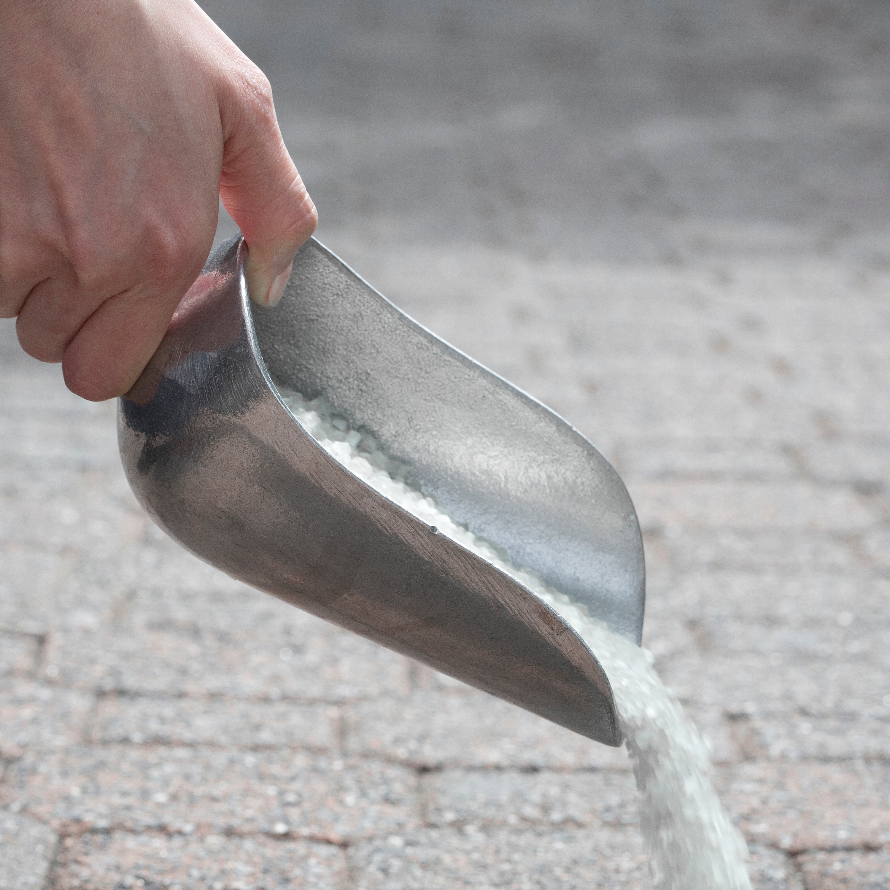 Snow Joe Calcium Chloride Blend Ice Melt being poured from the scooper.