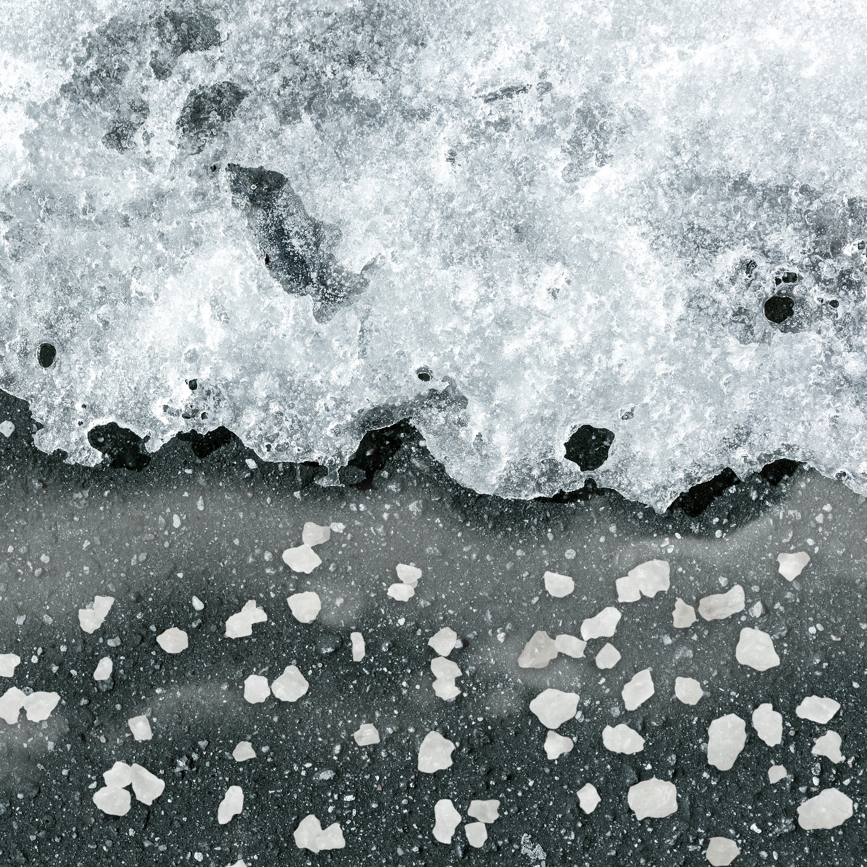 Rock salt ice melt melting ice on a driveway.