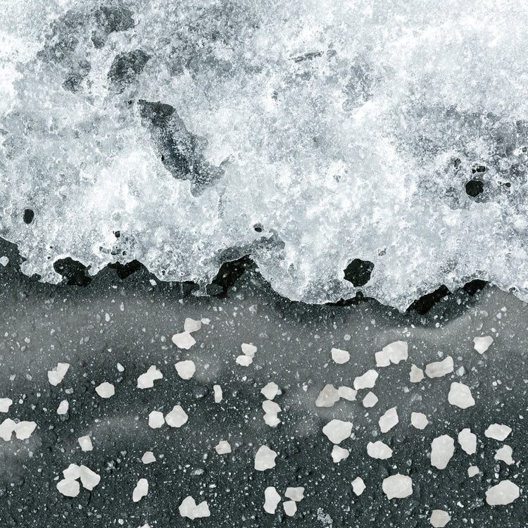 Rock salt ice melt melting ice on a driveway.