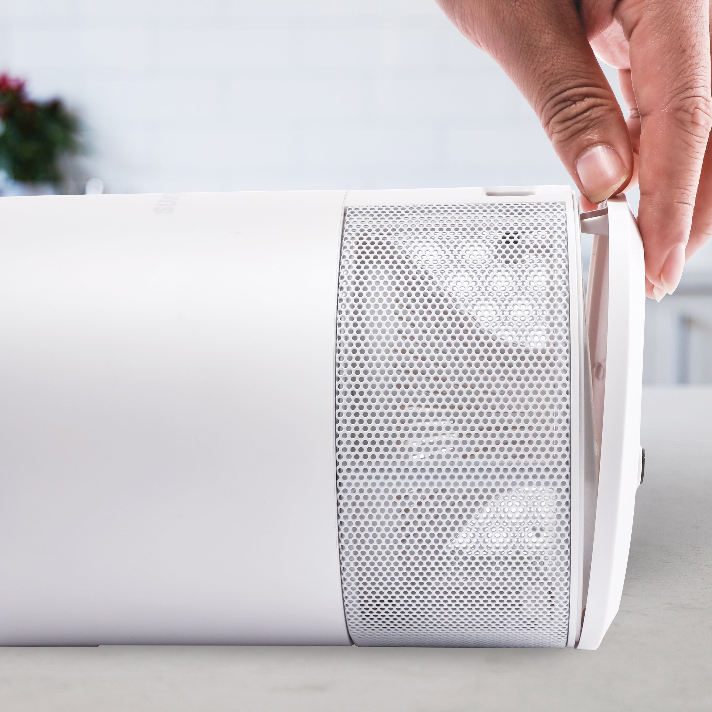 Person unlatching the tray on the bottom of the Sun Joe white non-toxic UV Indoor Insect Trap.