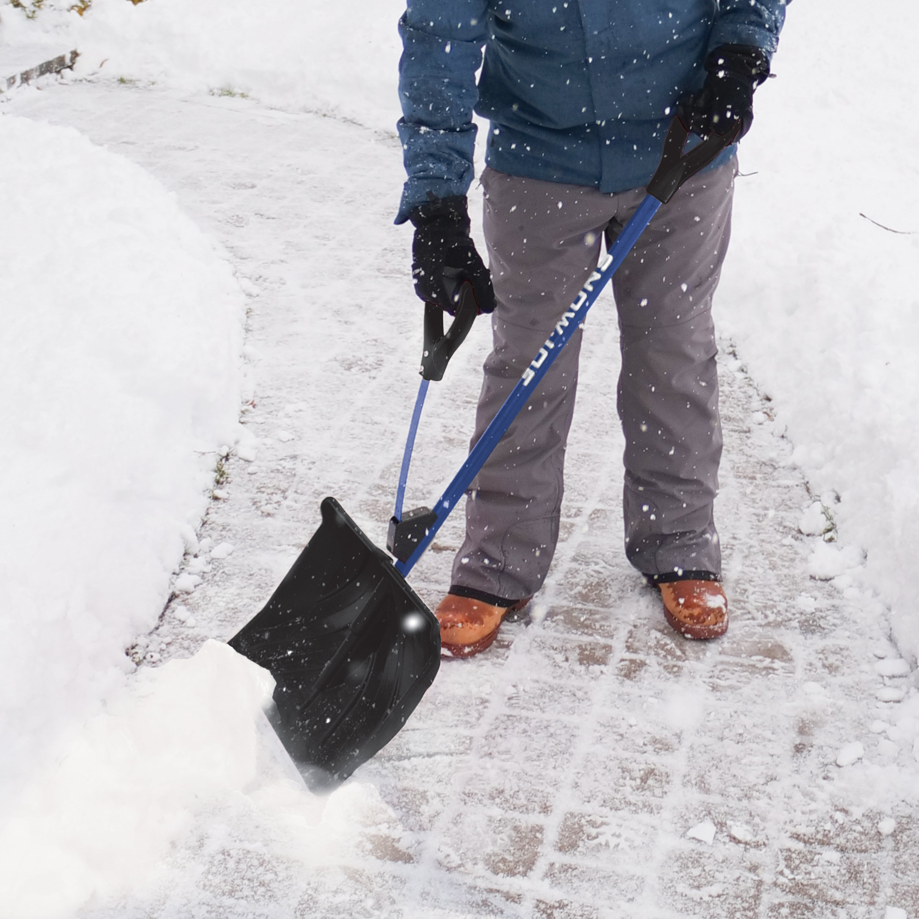 Snow Joe 20-inch Blue Shovelution Strain-Reducing Snow Shovel with spring assisted handle being used to throw snow off a walkway.