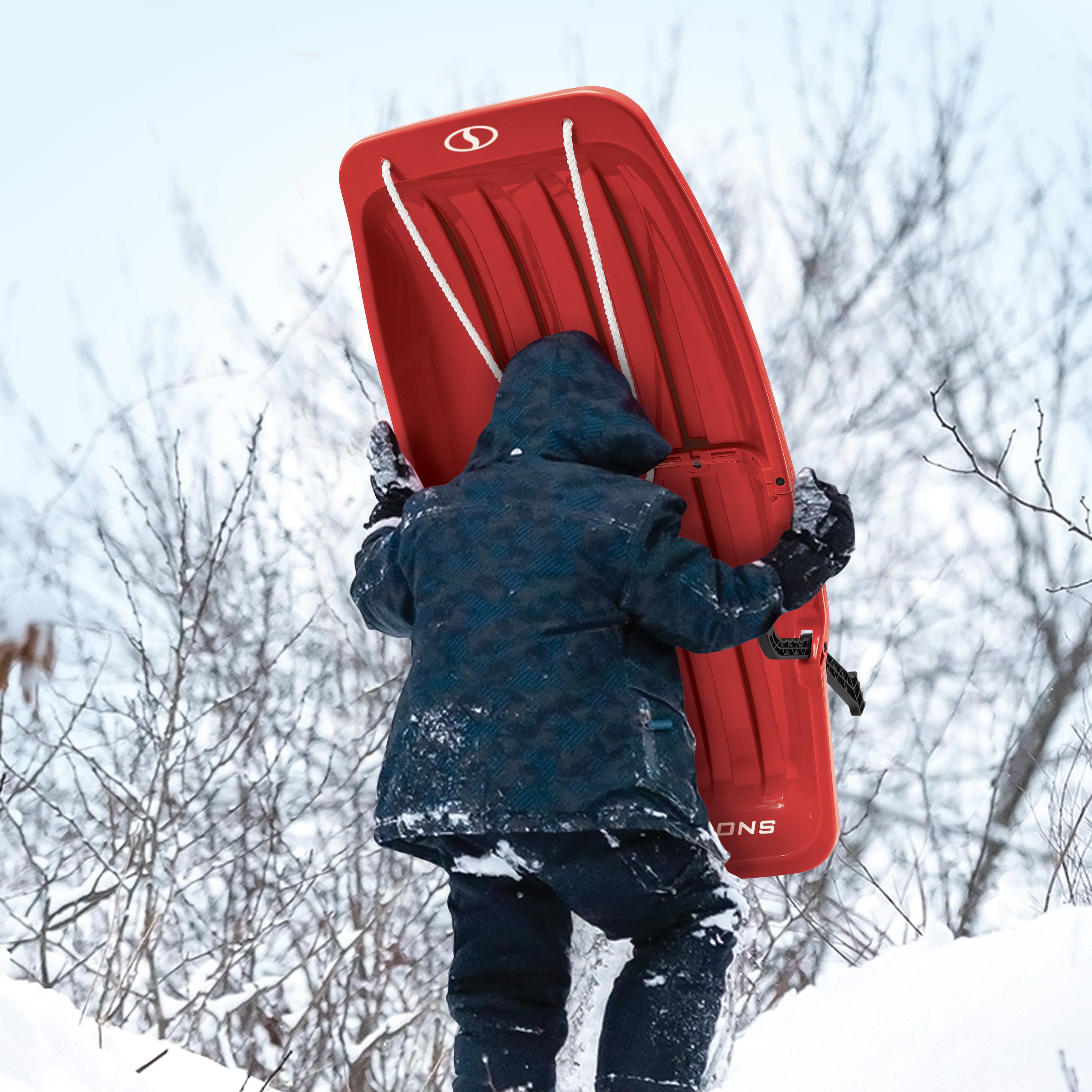 Kid carrying the Snow Joe 34-inch red-colored kids snow sled up a hill.