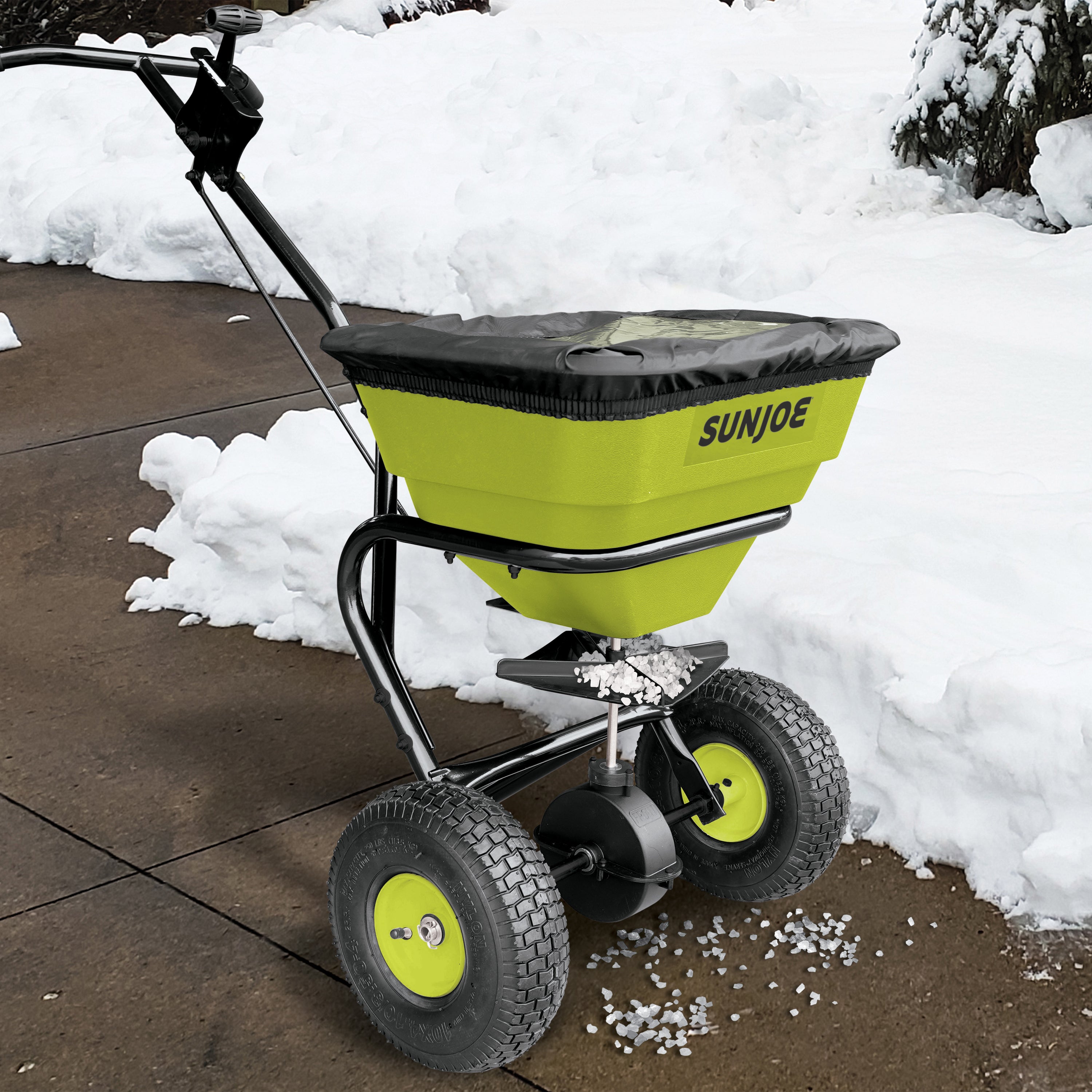 Sun Joe Multi-Purpose Walk-Behind Spreader being used to to spread ice melt on a walkway.