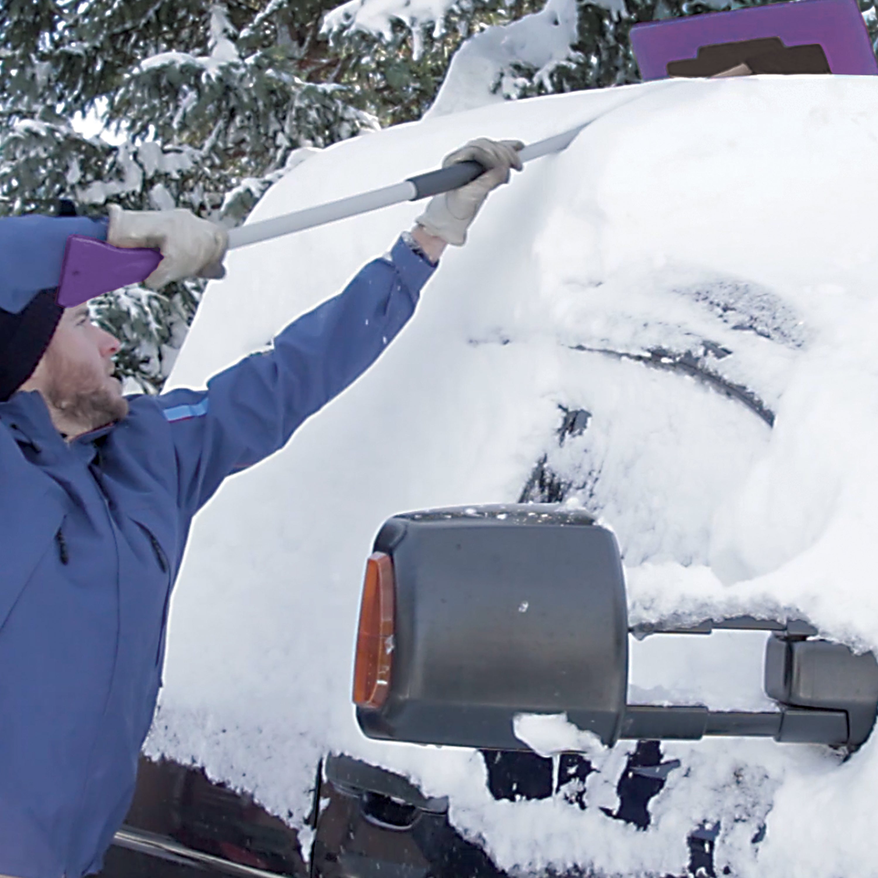 Snow Joe 19-inch 2-In-1 Telescoping purple Snow Broom and Ice Scraper being used to push snow off the top of a car.