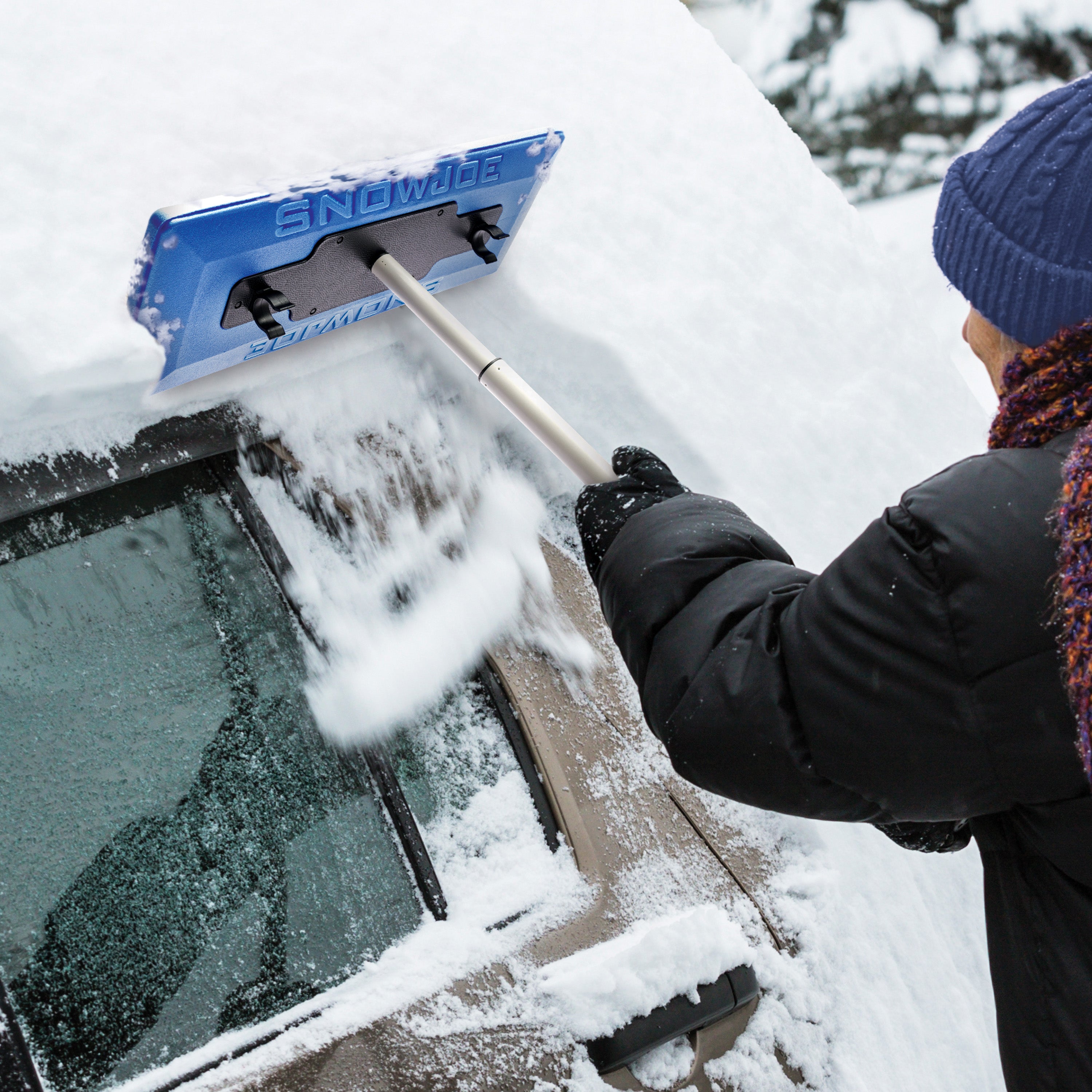 Person clearing snow off the side of the car with the snow broom.