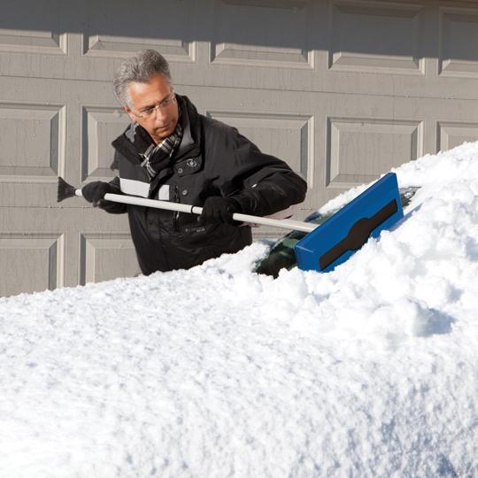 Snow Joe 18-inch 2-In-1 Telescoping Snow Broom and Ice Scraper being used to push snow off a car windshield.