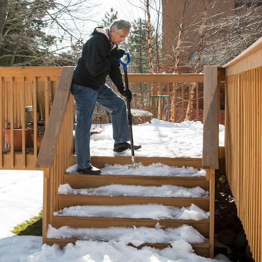 Snow Joe 24-inch 2-in-1 Snow Pusher and Ice Chopper being used to chop ice on patio steps.