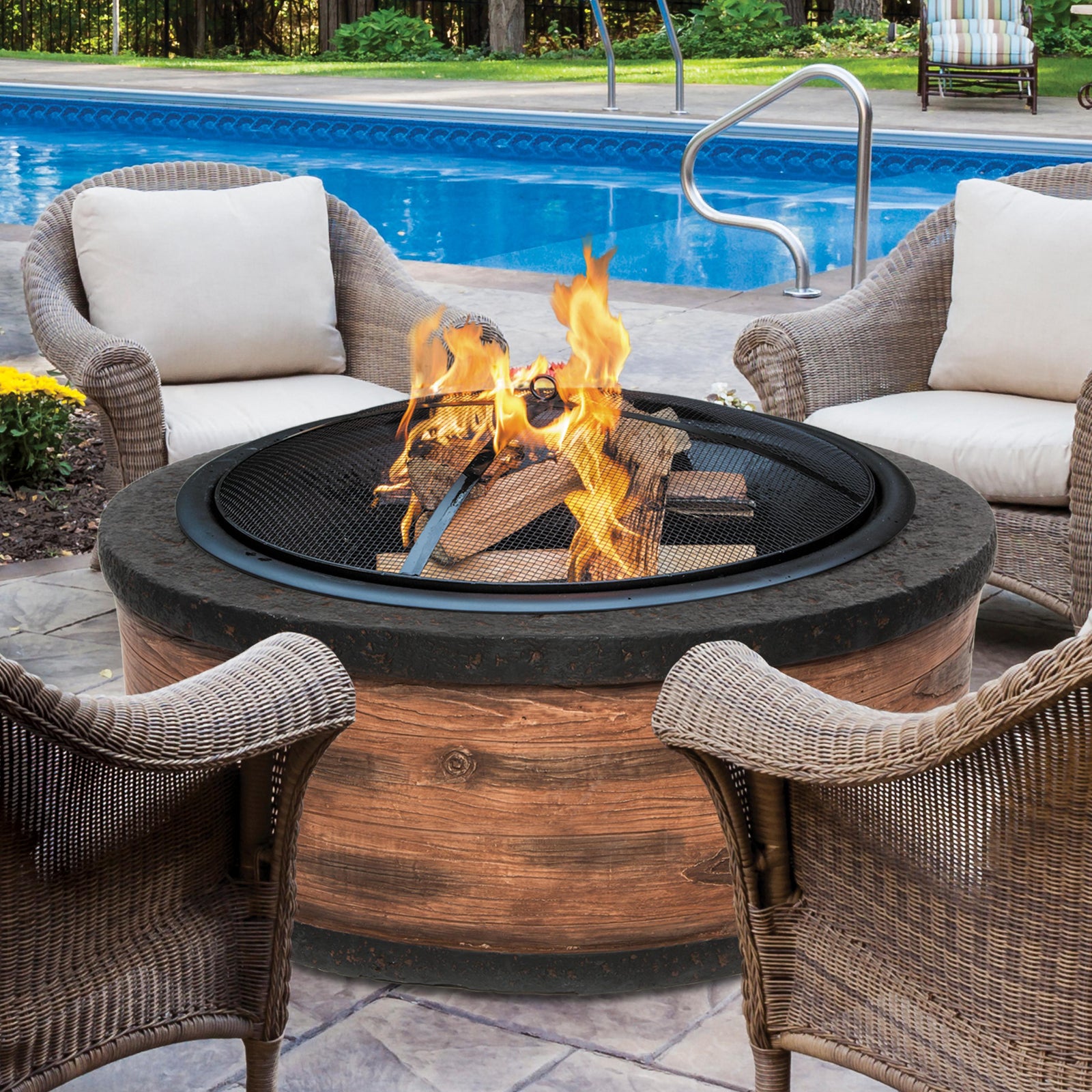 Fire going in the Sun Joe 35-Inch Rustic Wood Cast Stone Base, Wood Burning Fire Pit with patio chairs around it.