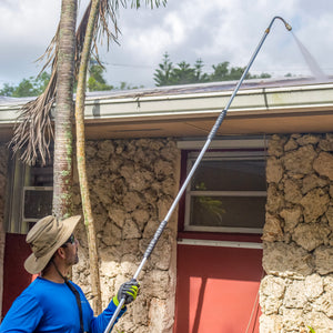 Man using the gutter cleaning attachment for SPX series pressure washers to clean the gutters of a house.