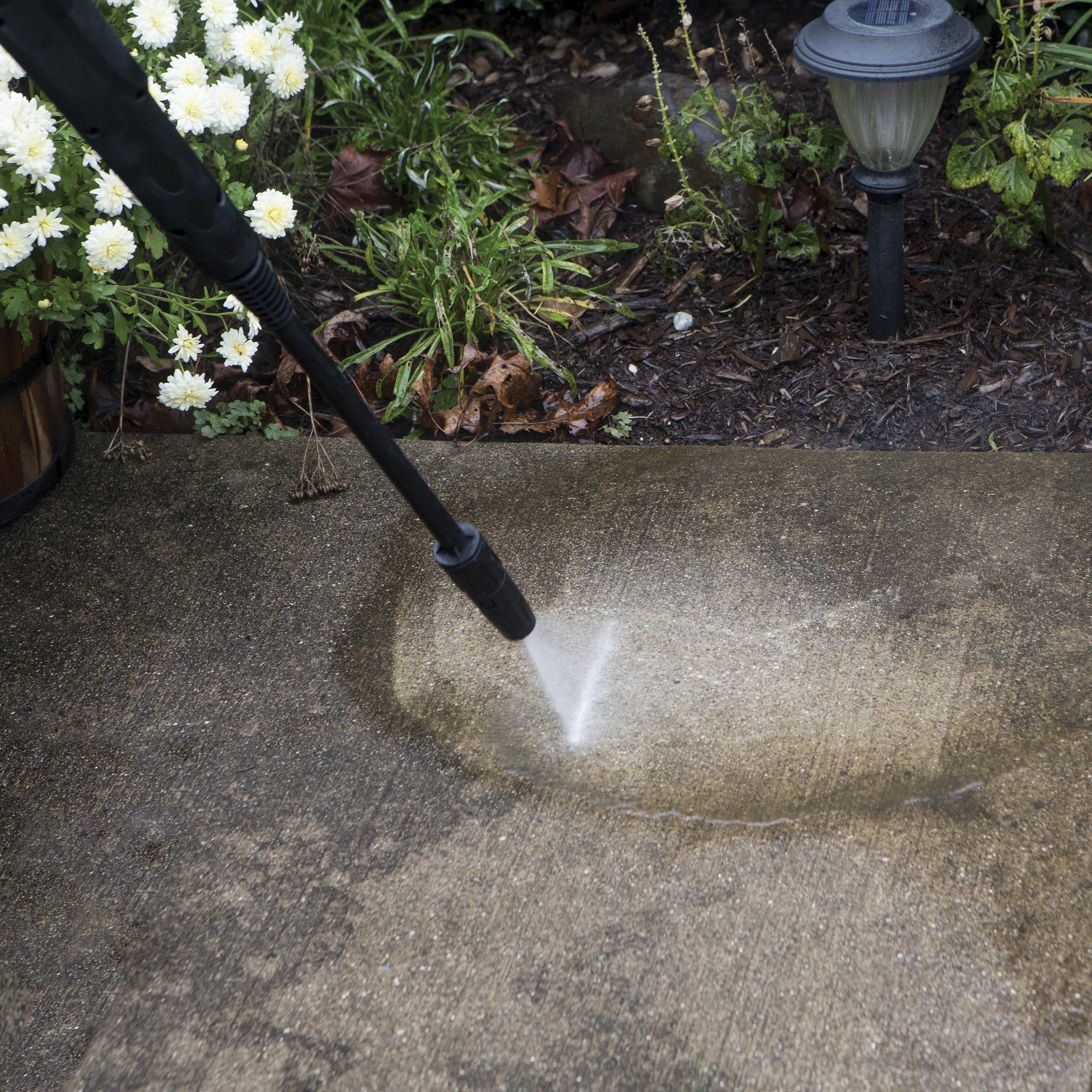 Spray wand being used to clean dirt off of cement.