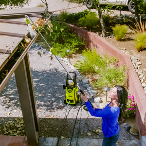 Spray wand for the Sun Joe 13-amp 2200 PSI Extreme Clean Electric Pressure Washer being used to reach high and clean the gutters of a house.